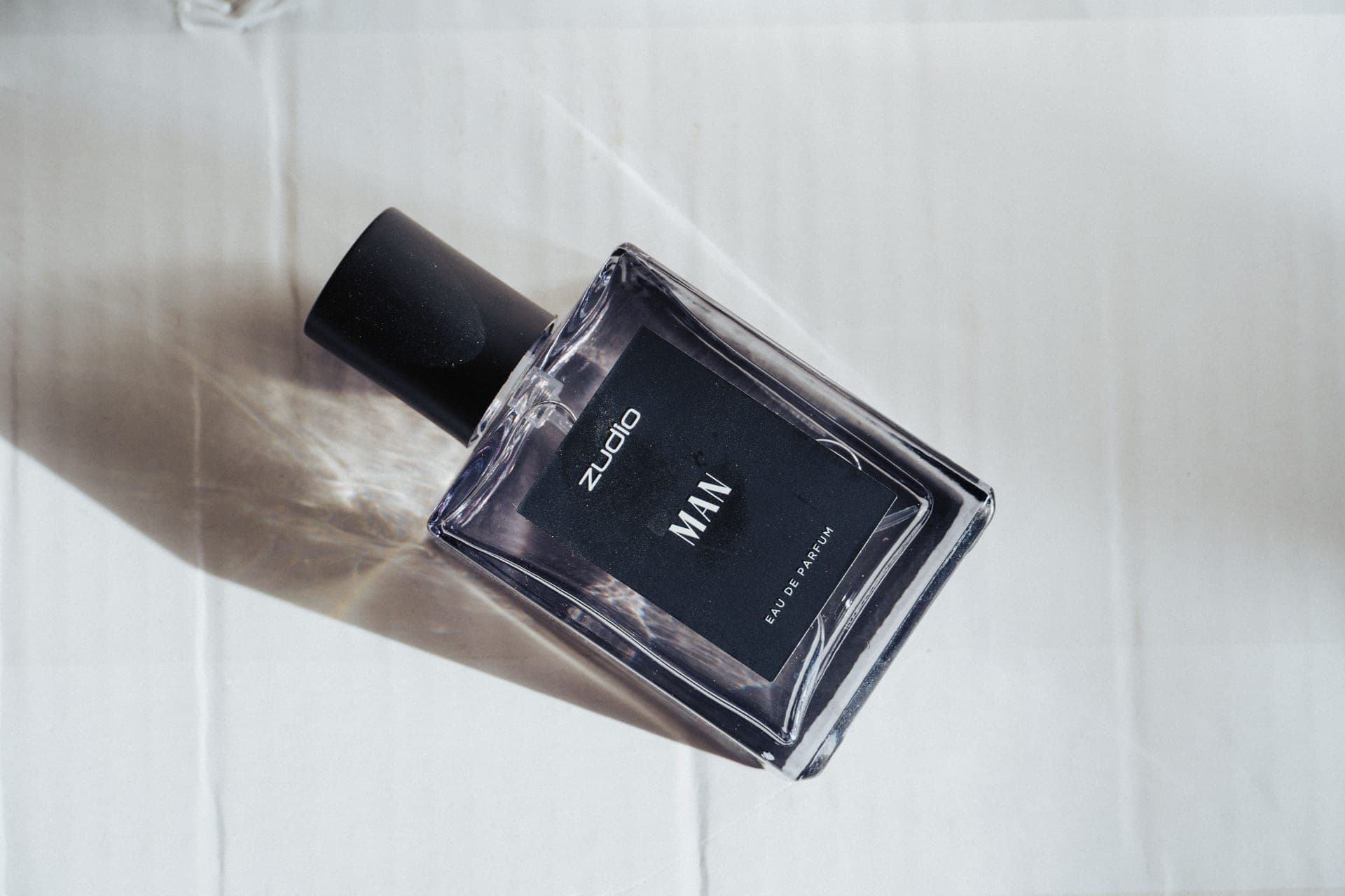 A glass bottle of men's cologne on warm parchment in natural daylight